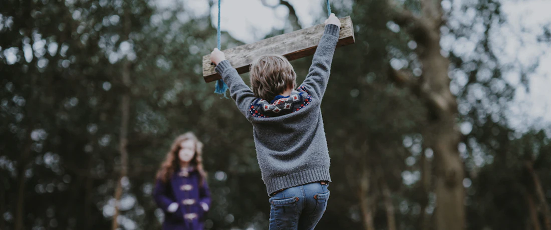boy holding on swing bench